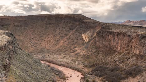 Der-Schlammige-Jungfräuliche-Fluss-In-Einer-Schlucht-Mit-Einer-Sonnenuntergangswolkenlandschaft-Darüber---Zeitraffer