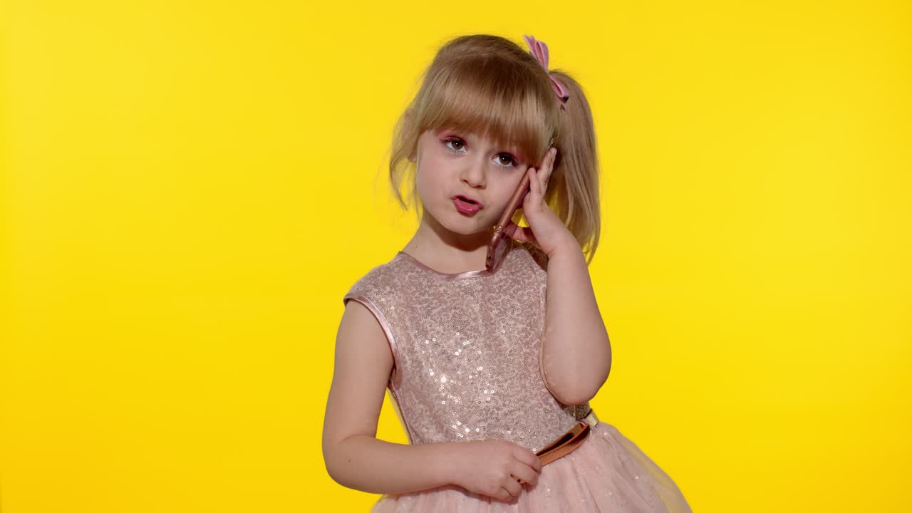 niña sonriente de 5-6 años usando hablar hablando en teléfono móvil llevando a cabo una conversación