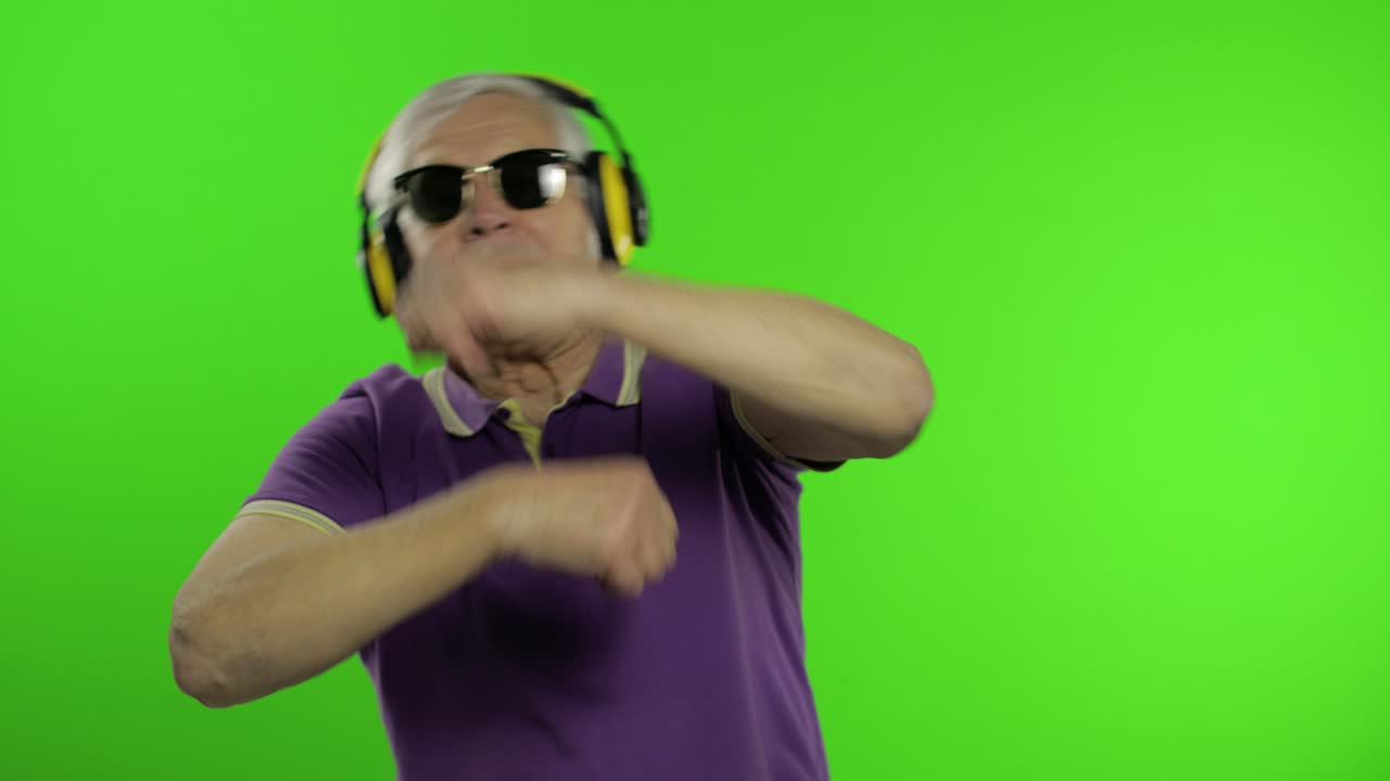 Äldre kaukasisk morfar/farfar turist dansar, lyssnar på musik. Chroma key