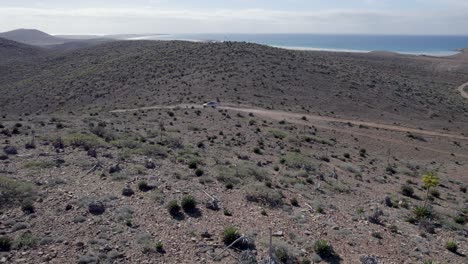 Aerial-drone-shot-of-a-truck-driving-away-from-the-beach-in-Baja-California,-Mexico