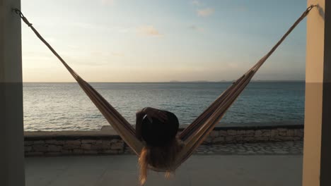 young woman swinging in a hammock in a beautiful sunset on bonaire, dutch caribbean, south america