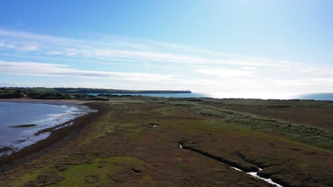 aerial flying over isolated green field near tramore beach, ireland