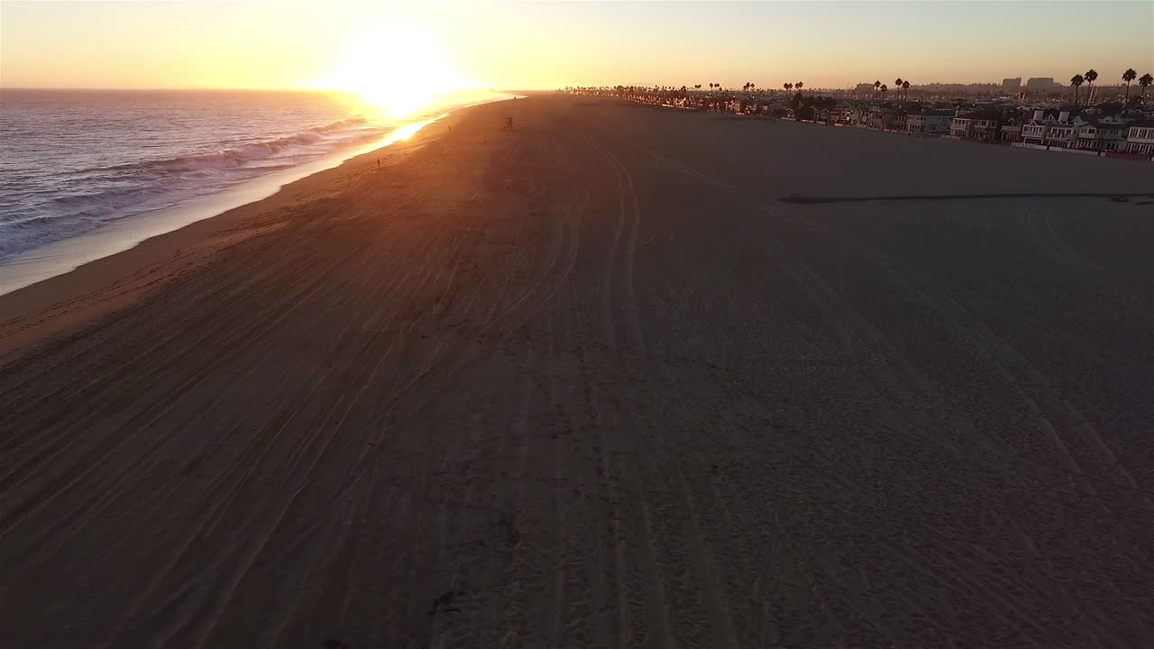 Aerial drone footage of sunset over ocean moving to beach front homes on Balboa Island in Orange County, California