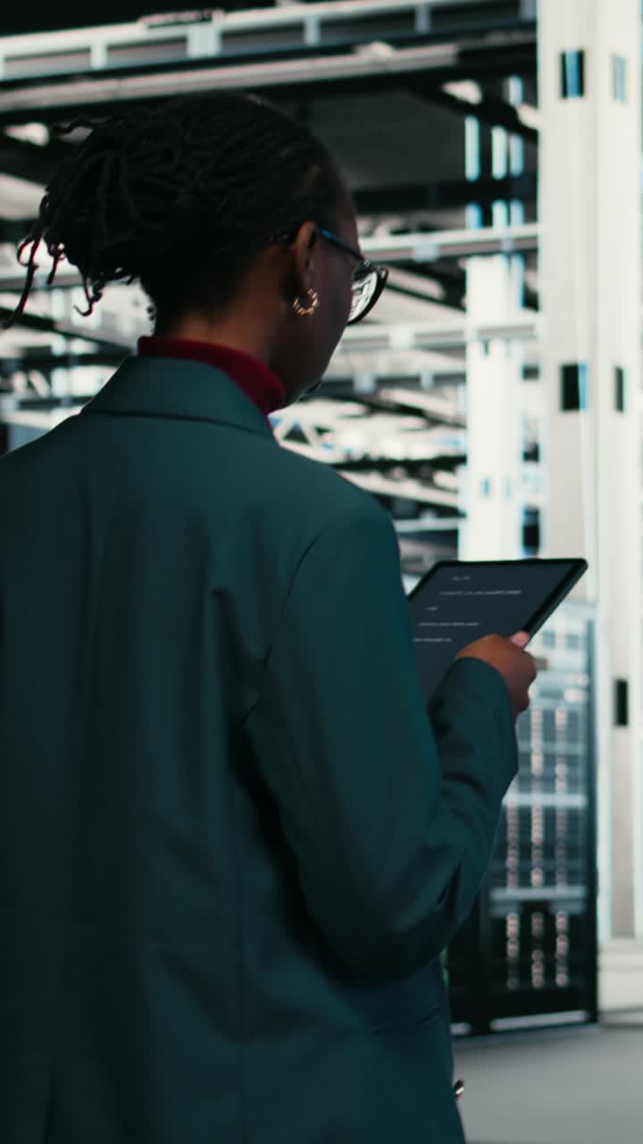 Vertical video Writing code, tablet and female programmer walking in data center