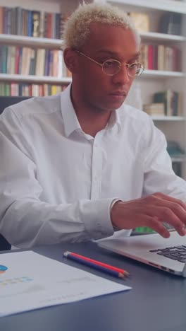 serious african american man office worker pulls hands to laptop sits in office
