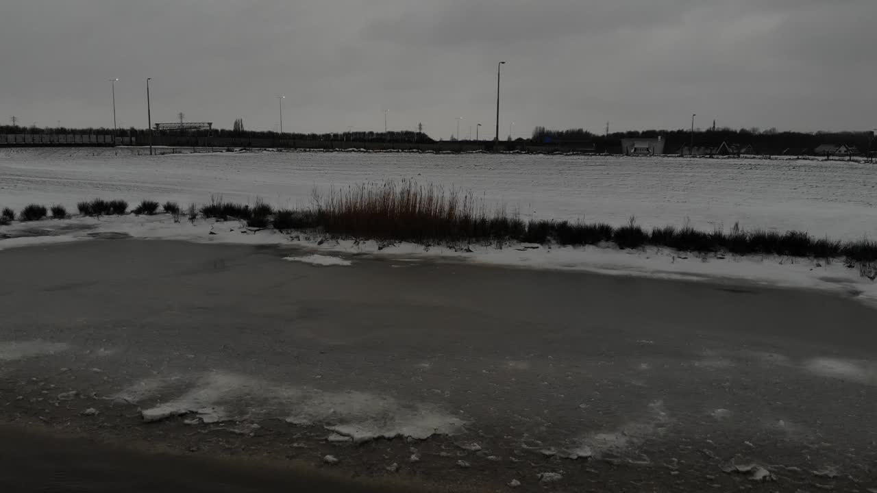 Part Of Lake Frozen And Snow-covered Field Under The Cloudy Sky. aerial