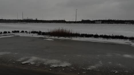 part of lake frozen and snow-covered field under the cloudy sky. aerial