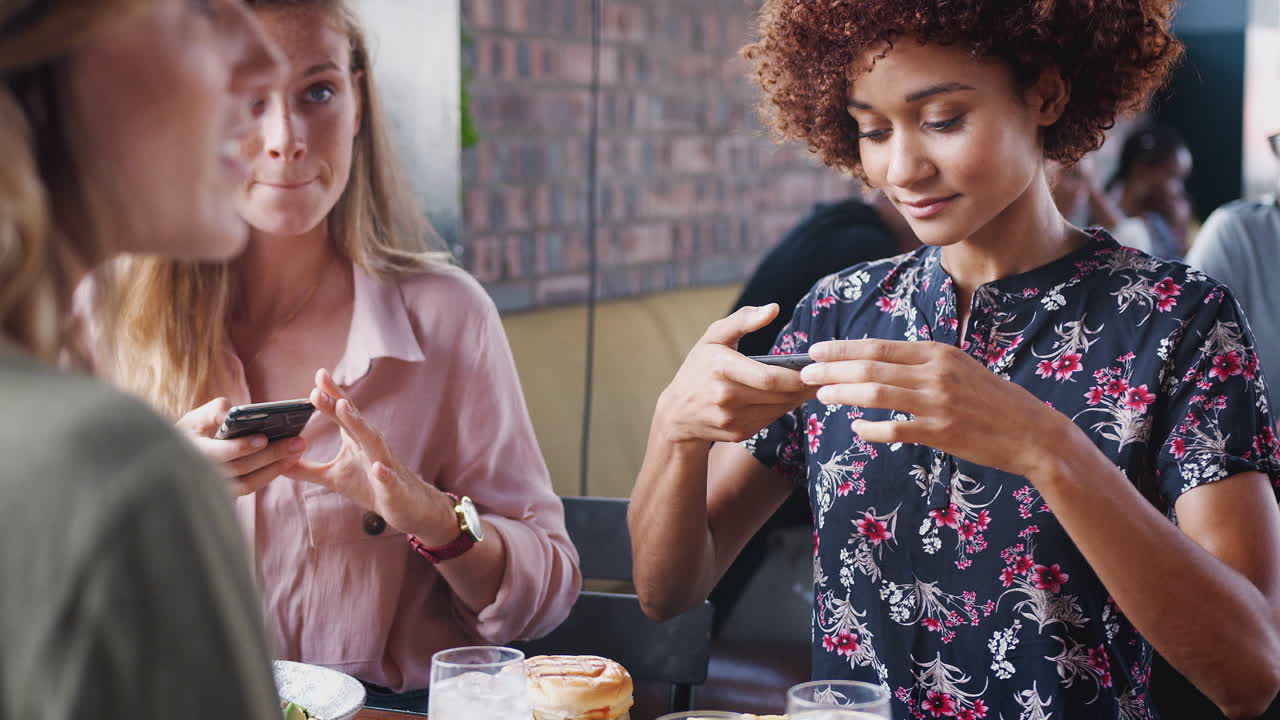 cuatro amigas tomando fotos de comida en un restaurante para publicar en las redes sociales
