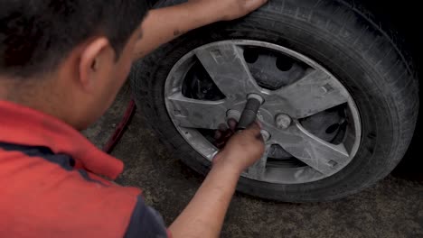 young latino brown expert mechanic manually tightening wheel lug nuts with tools in latinamerican car garage