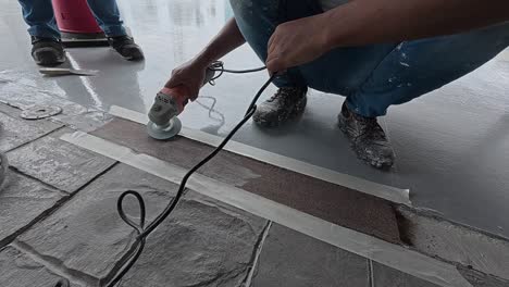 uneven concrete patching is being ground smooth by a construction worker using an electric grinder. safety is the top priority for this meticulous work.