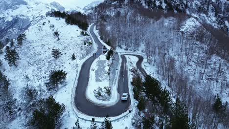 aerial snow covered mountain range with u-turn road in the albanian mountains of teth