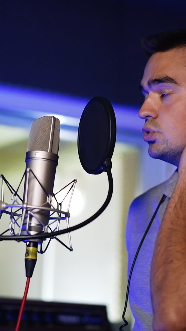 Male Caucasian singer performing song in the modern studio. Man sings a lyrical composition and then starts laughing. Vertical video