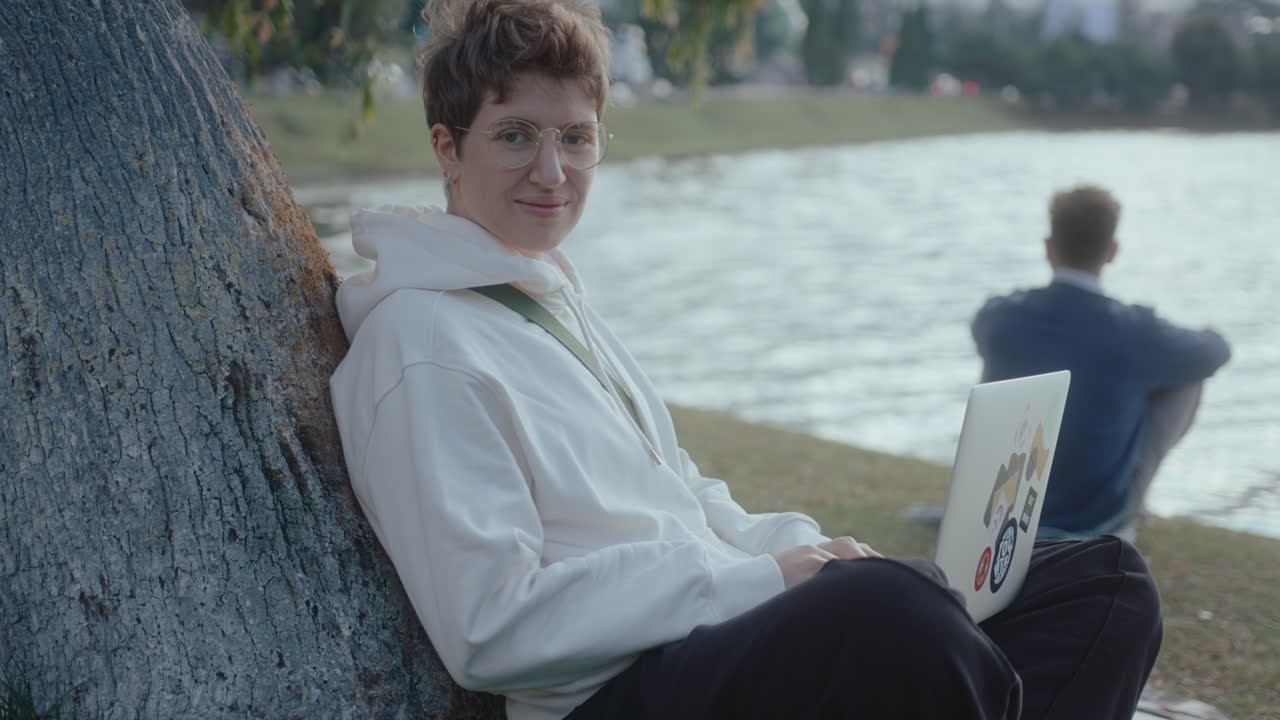 Young Woman Sitting in the Park with Laptop Posing on Camera