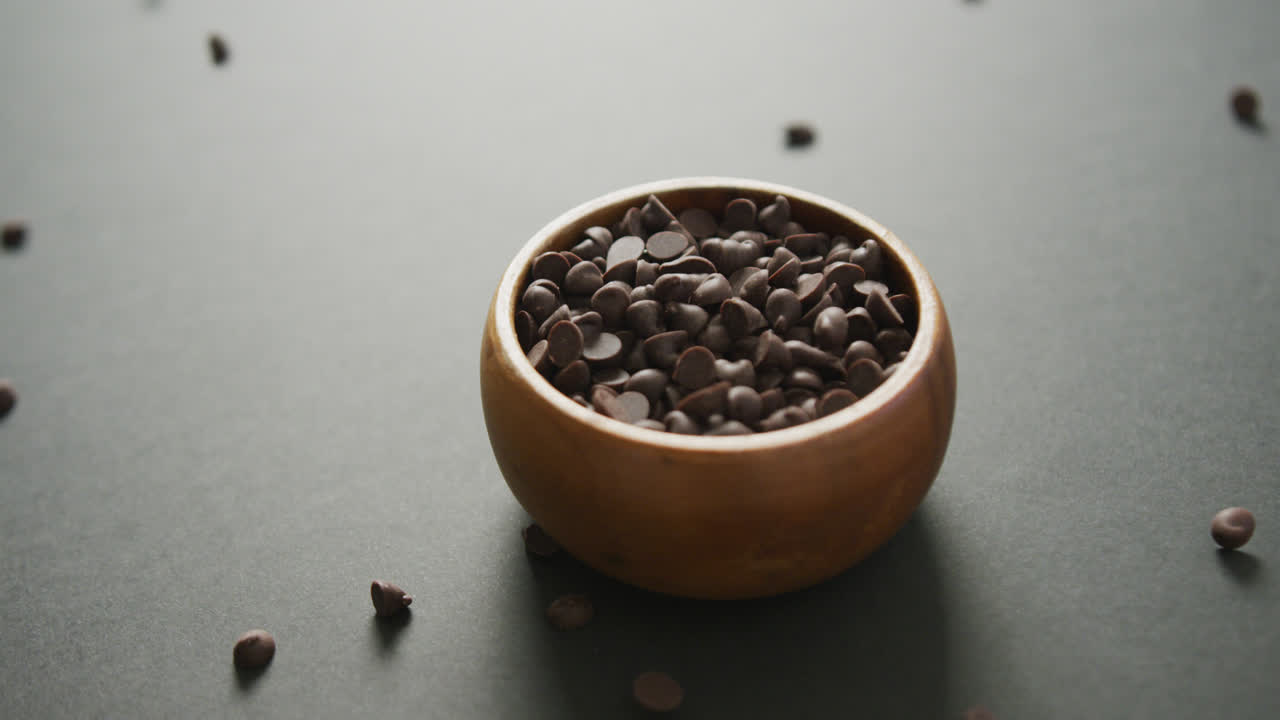 Video di ciotola di legno di gocce di cioccolato su sfondo grigio
