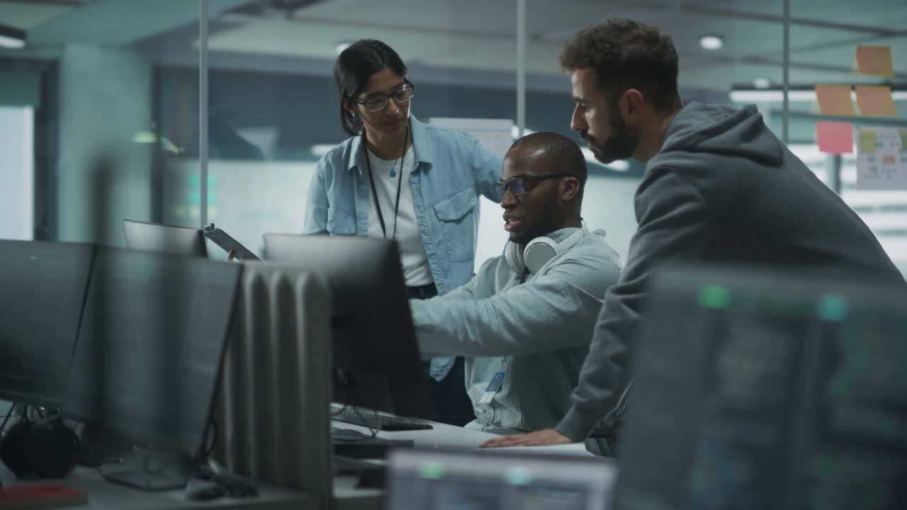 Diverse Multi-Ethnic Team in Modern Office: Teamwork of IT Programmers Gather Around Desktop Computer, Talking, Finding Solution. Specialists Create Software. Engineers Develop App, Program
