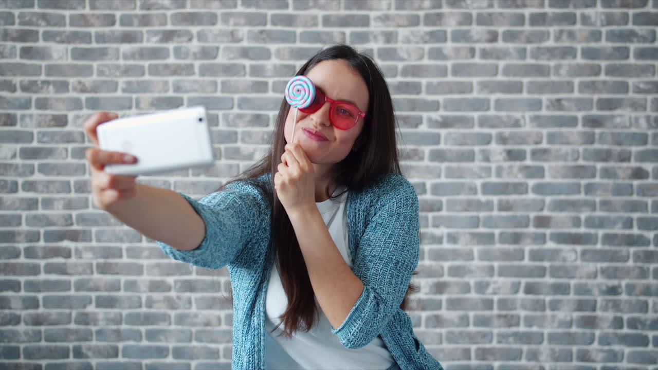 Woman taking a selfie with a lollipop