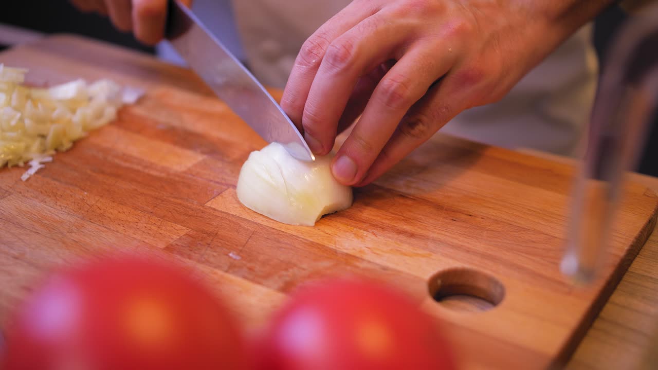 cook cuts the onion on a wooden board