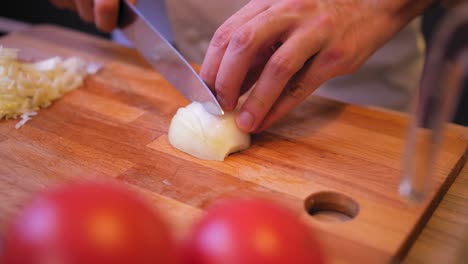 cook cuts the onion on a wooden board