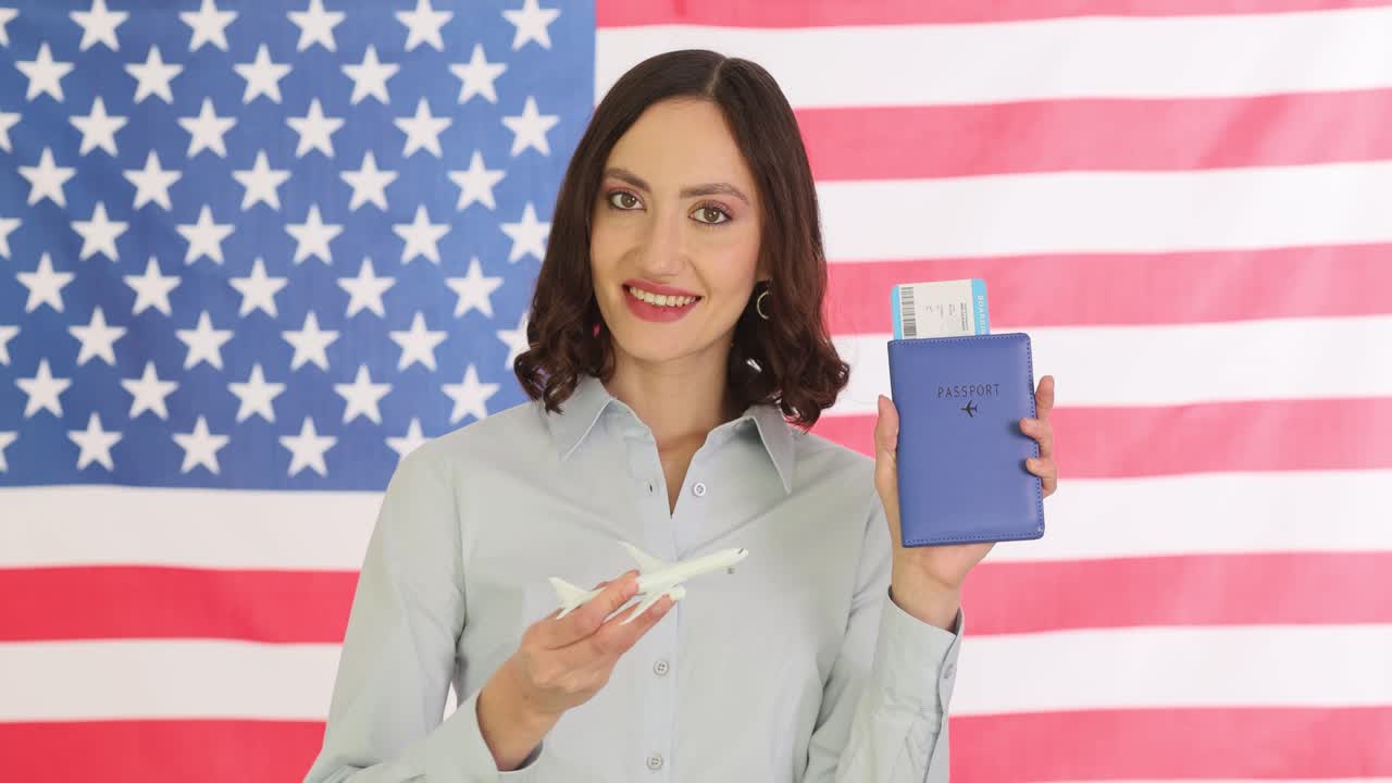 Smiling lady traveler holds passport and plane model by usa flag