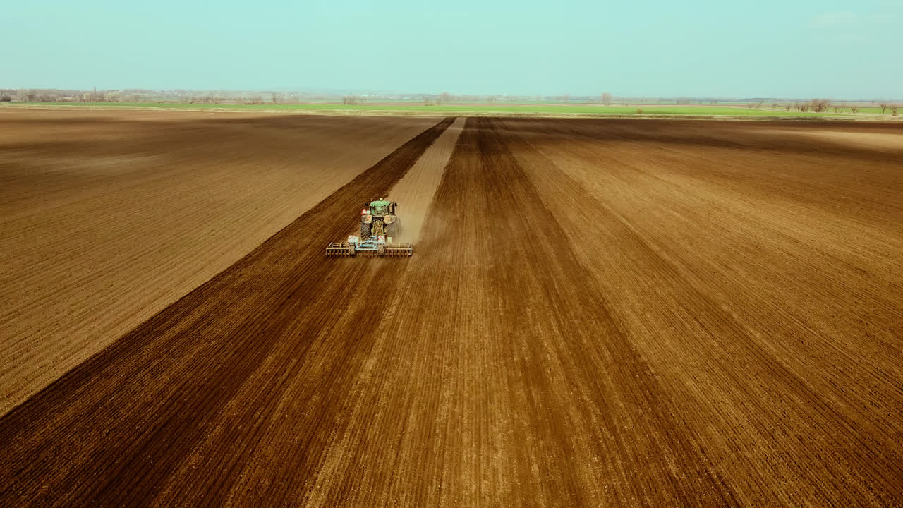 aerial shot of tractor plows field, open semi arid agricultural landscape