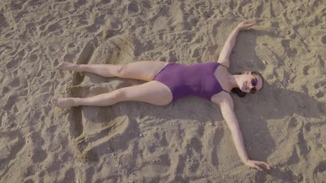 Top-view-of-attractive-girl-doing-sand-angels-on-a-beach