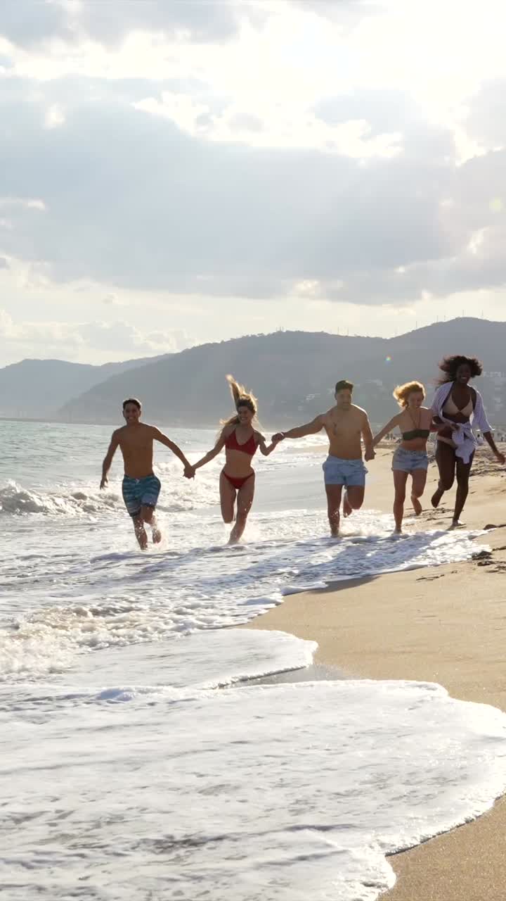 Group of friends running on the beach