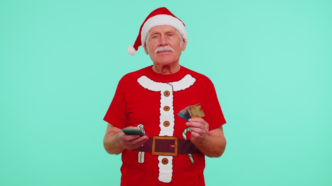Christmas grandfather using credit bank card smartphone while transferring money shopping online