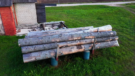 Pile-of-logs-ready-to-be-cut-in-local-sawmill-area,-aerial-dolly-forward