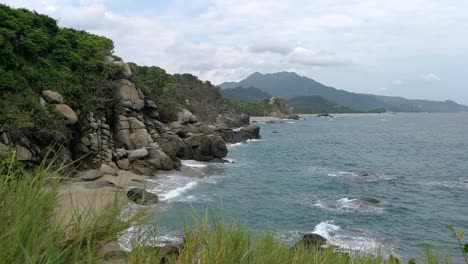 rocky coastline with waves rolling on beach in colombia at atlantic ocean coast in tayrona park, locked off