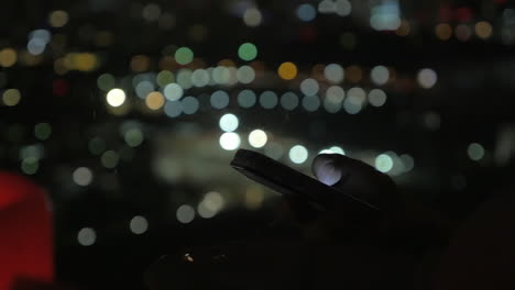 navegando en el teléfono inteligente por la noche luces de la ciudad en el fondo