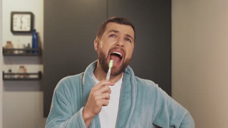 a cheerful man sings and brushes his teeth in the bathroom