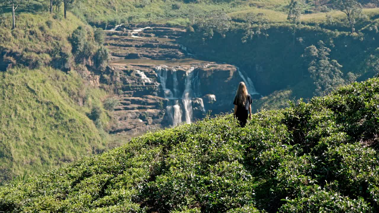 Footage of a woman walking through lush tea plantations at Saint Clair’s Falls in Nuwara Eliya, Sri Lanka.
