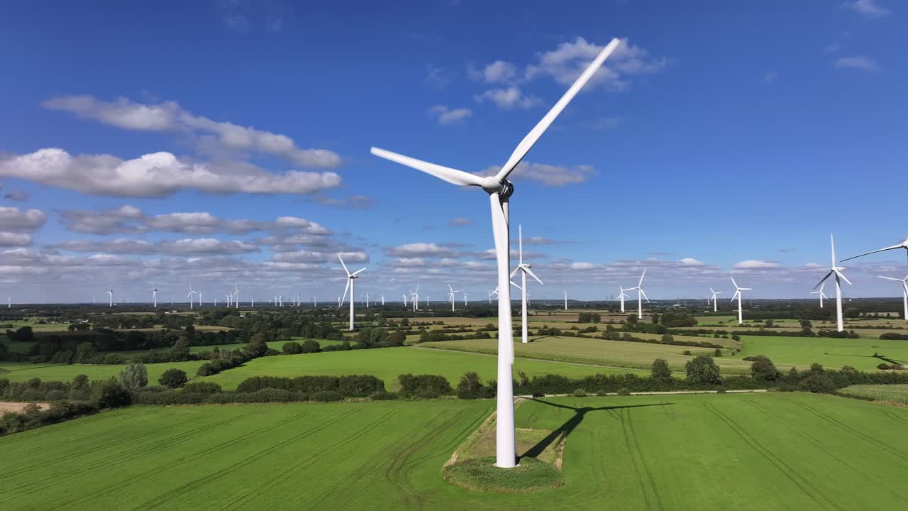 Wind turbines farming wind energy, green fields, blue sky, countryside, sunny, slow drone orbit, slow shutter