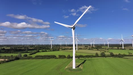 Wind-turbines-farming-wind-energy,-green-fields,-blue-sky,-countryside,-sunny,-slow-drone-orbit,-slow-shutter