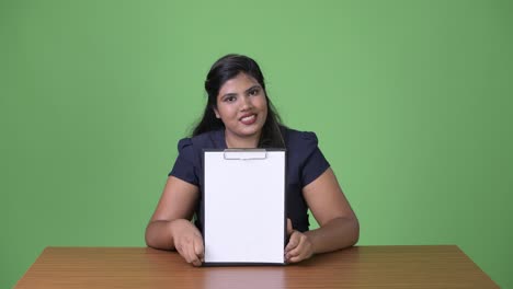 young overweight beautiful indian businesswoman against green background