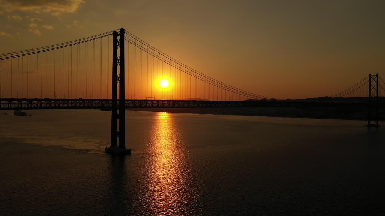 Luftaufnahme der Silhouette der Ponte 25 de Abril bei Sonnenuntergang, Lissabon.
