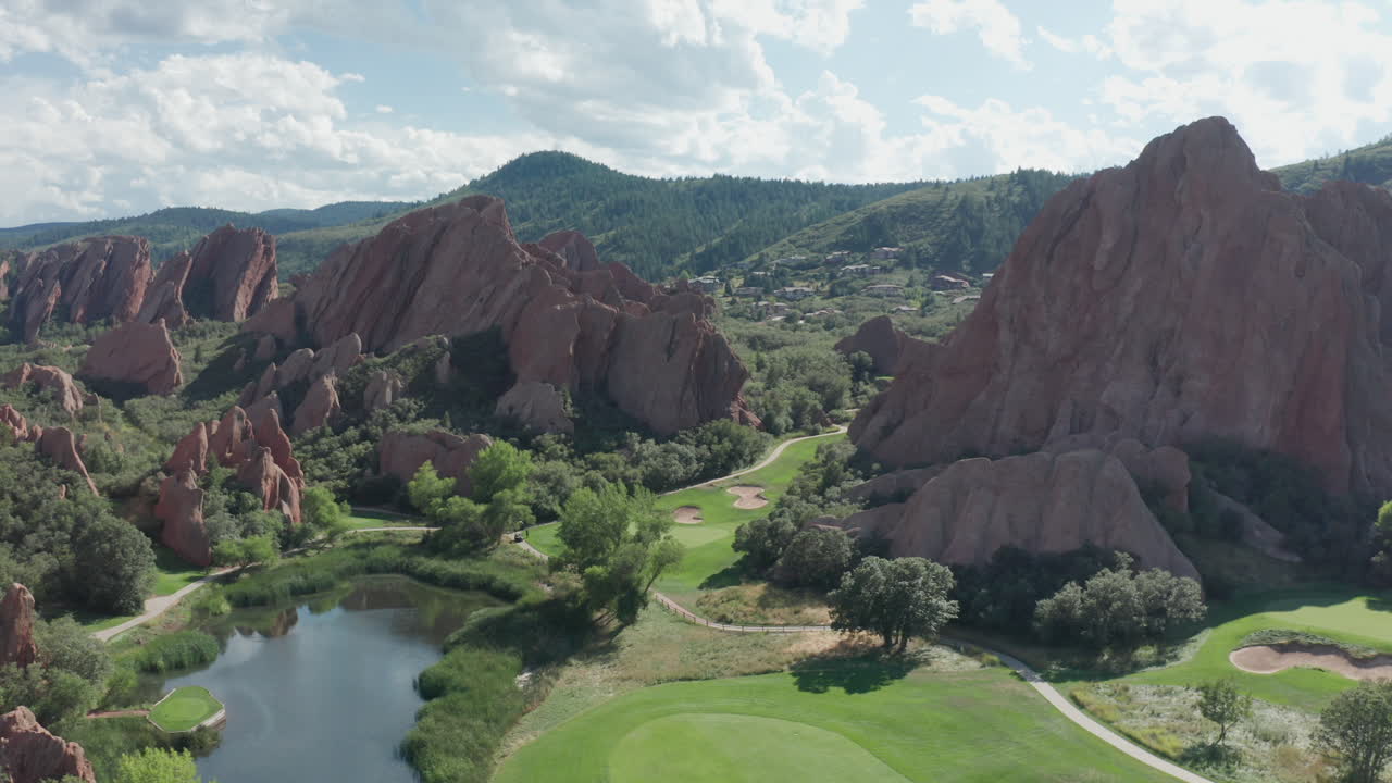 курортное поле для гольфа arrowhead в литлтоне, штат колорадо, с зеленой травой, красными скалами и голубым небом