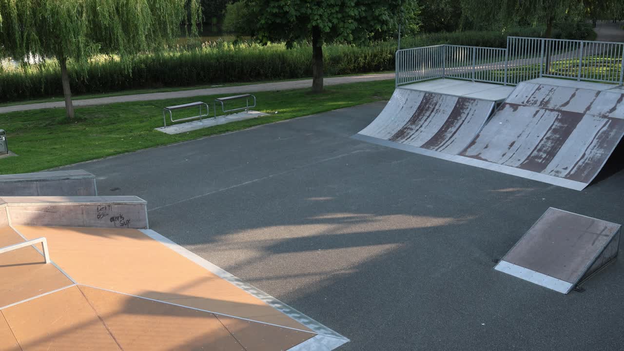 Skateboard park with ramps in a park, wide overhead establisher