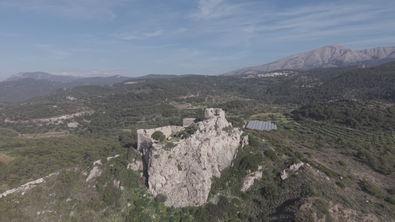 Aerial drone footage of the historic Kritinia Castle ruins on Rhodes island, Greece. The medieval fortress sits dramatically on a hilltop overlooking the Aegean Sea. D-Log M