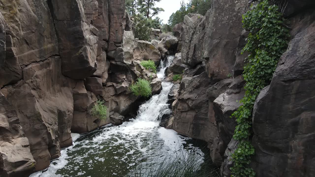 retroceso aéreo de una cascada en un barranco que desemboca en un pequeño estanque