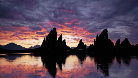 sunrise over dramatic mountain peaks and calm lake