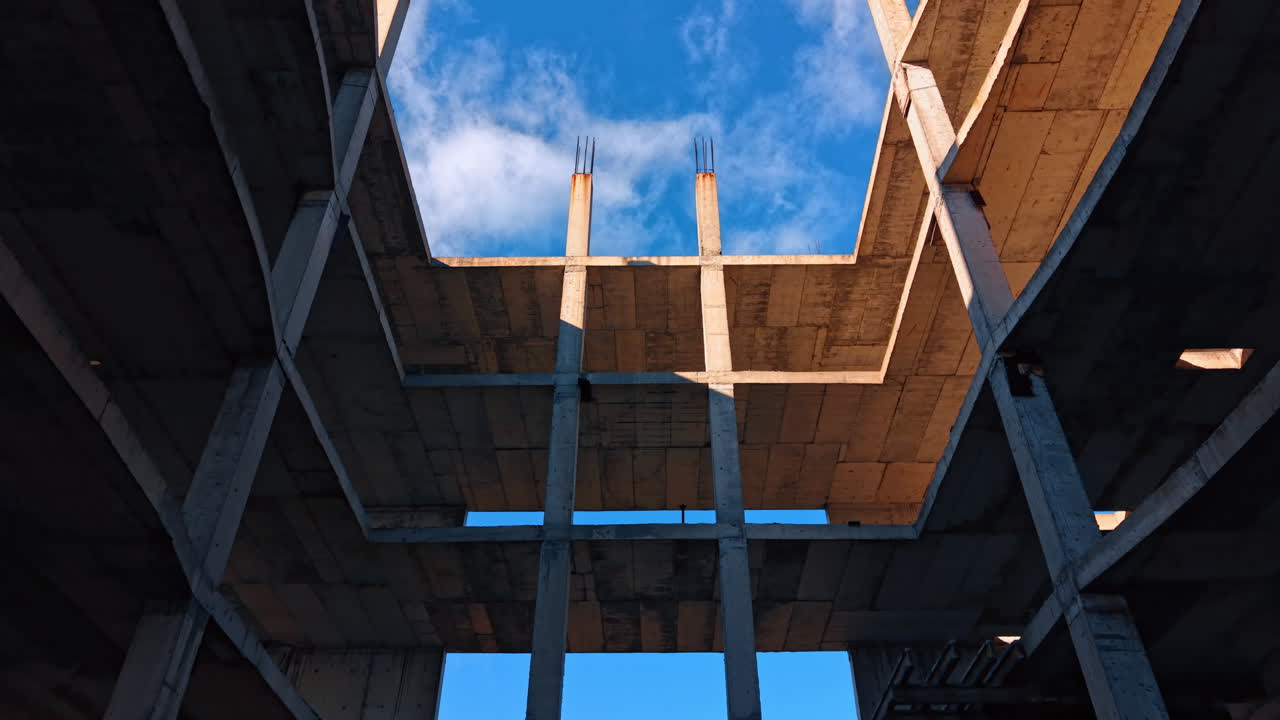 Empty space inside the building under construction. Rebars are on the roof of the structure. Blue sky at backdrop