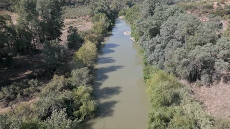 A-leisurely-drone-aerial-above-the-Guadalquivir-River-in-Marmolejo,-Jaén-province,-Spain,-showcasing-the-allure-of-its-natural-surroundings-and-lush-scenery