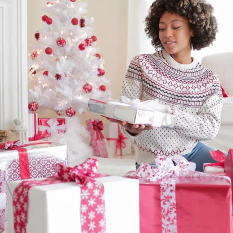 Smiling-young-woman-opening-her-gifts-at-Christmas