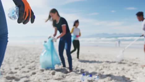 grupo diverso de amigas poniendo basura en bolsas de basura en la playa