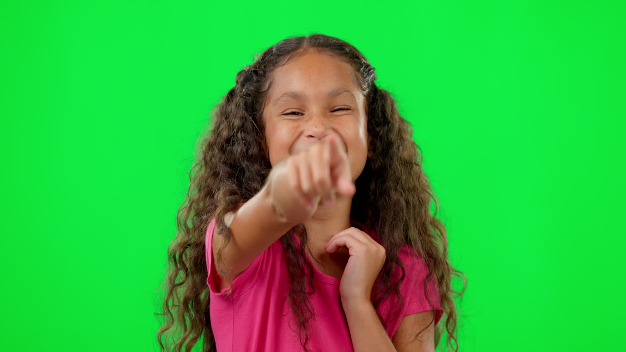 Bambina, schermo verde, che ride e indica