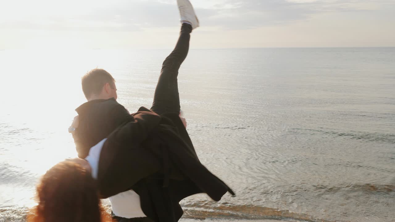joven hombre y mujer de moda, gente en la playa de arena, feliz pareja de adultos casados divirtiéndose, jugando, engañándose junto al mar en primavera o otoño. día cálido y soleado. 4k