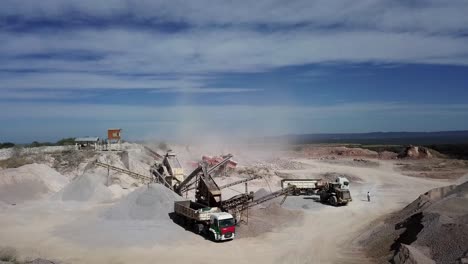 aerial-view-of-a-working-stone-quarry-with-stone-crushers,-bulldozers,-trucks-in-a-natural-environment-with-daylight