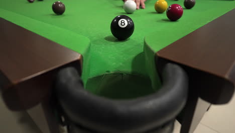 close-up moment as black eight-ball approaches pocket when the player hit it with cue