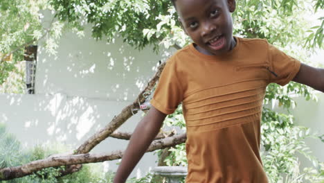 African-American-boy-with-a-playful-expression-stands-near-a-tree